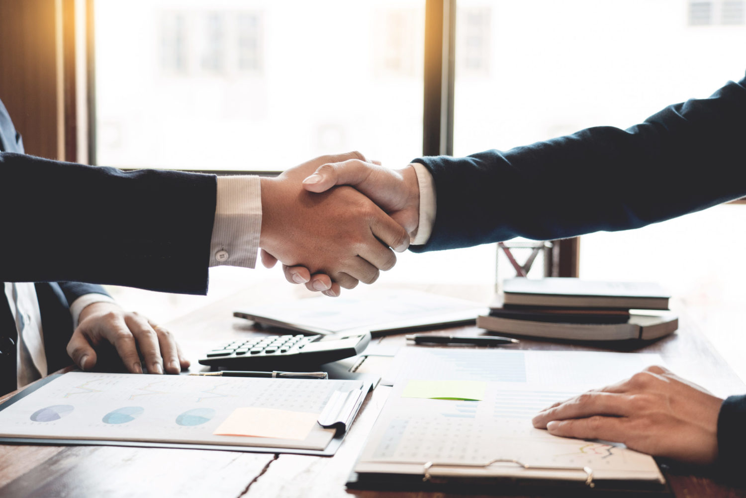 ROCs, REGOs, and PPAs agreements. Two people shaking hands over documents on a table