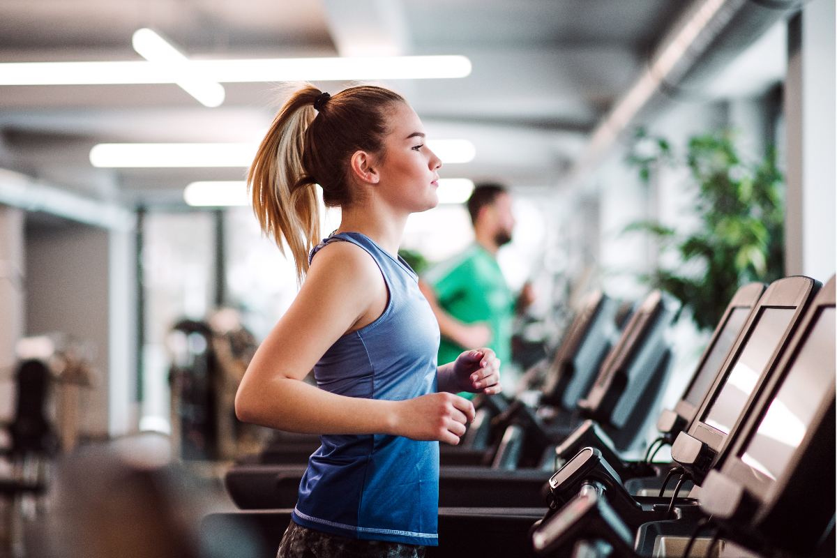 A woman in a gym using a treadmill