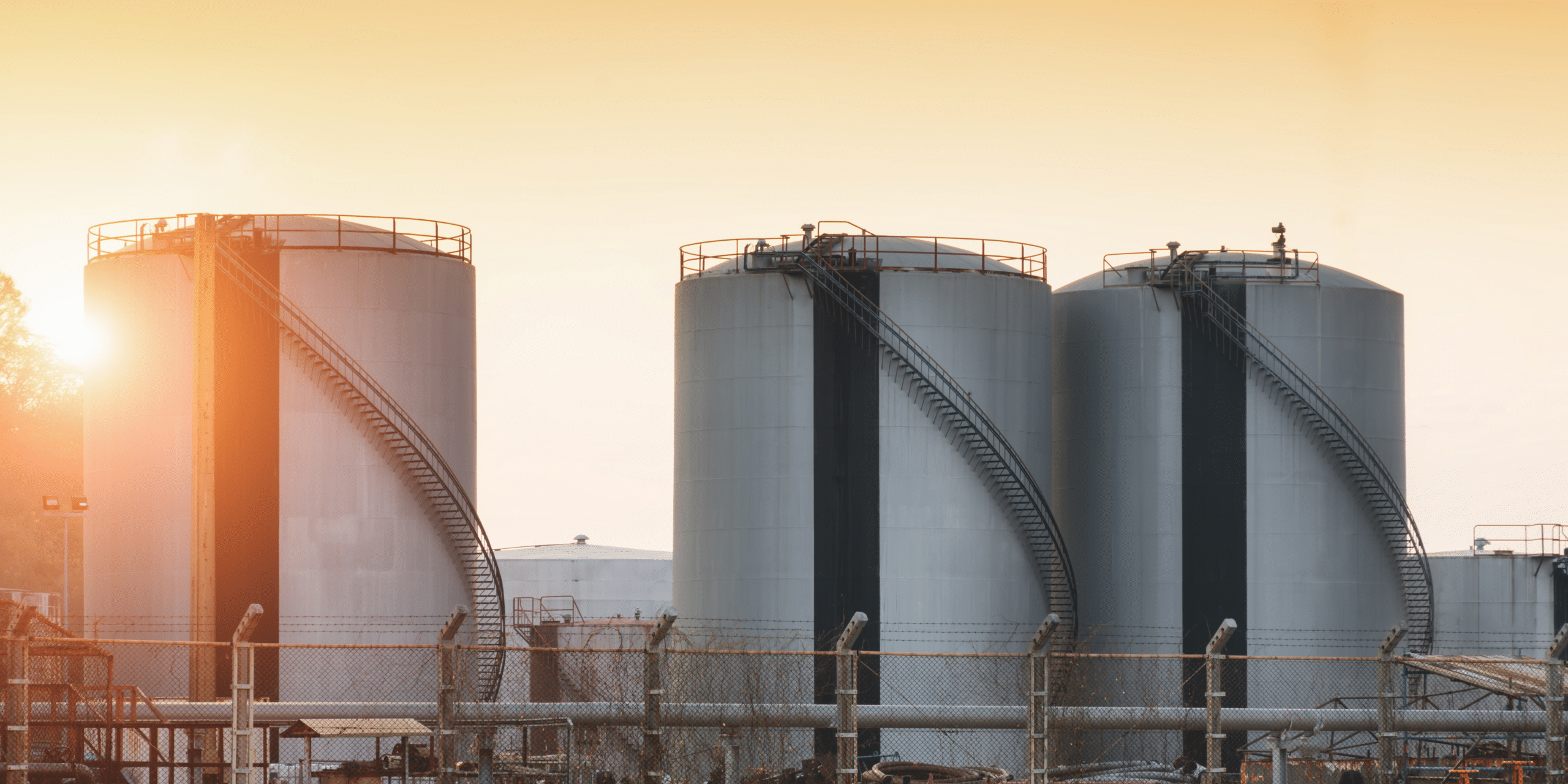 Large industrial gas storage tanks at sunset, highlighting European gas storage levels and potential wholesale gas price volatility ahead of winter 2026/27.